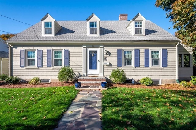 cape cod-style house featuring a chimney, roof with shingles, and a front yard