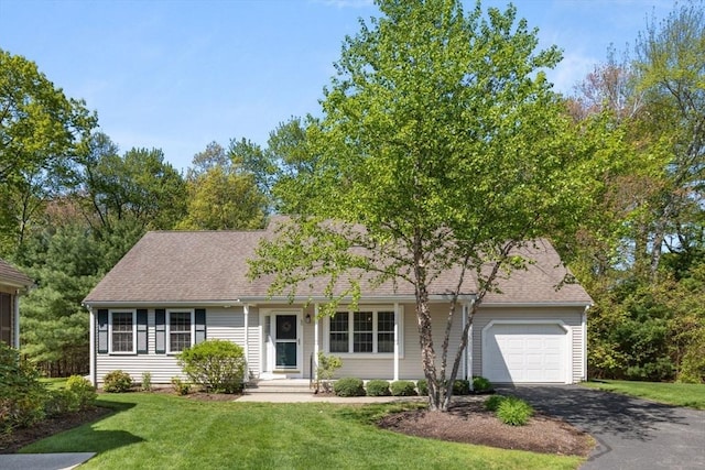 view of front of house featuring an attached garage, driveway, a front yard, and a shingled roof
