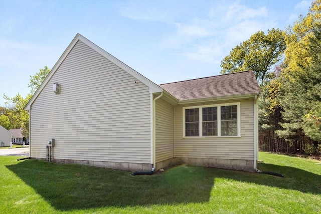 view of home's exterior with a yard and a shingled roof