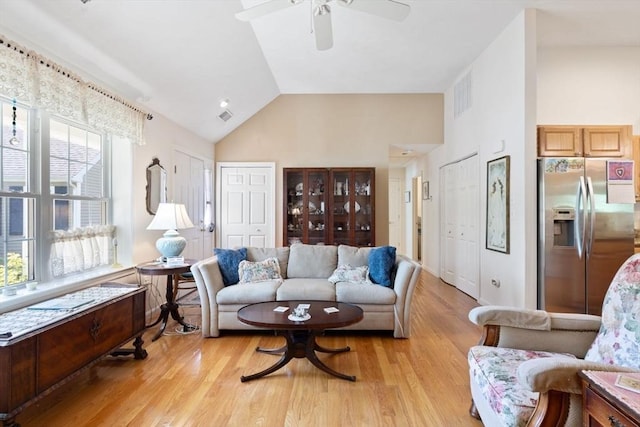 living room with ceiling fan, plenty of natural light, high vaulted ceiling, and light wood-type flooring