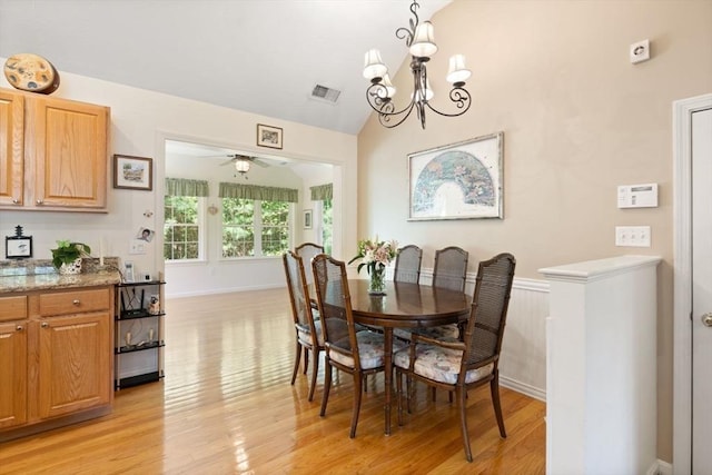 dining room featuring light wood finished floors, a chandelier, a ceiling fan, and vaulted ceiling