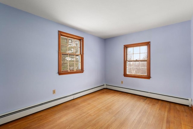 unfurnished room with baseboard heating and wood finished floors