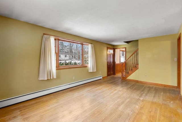 unfurnished room featuring a baseboard heating unit, wood-type flooring, stairway, and baseboards