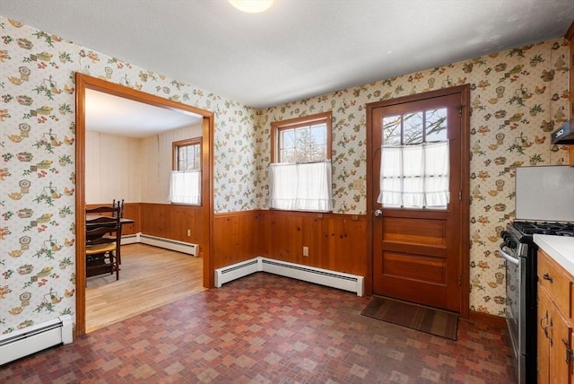 interior space featuring a wainscoted wall, baseboard heating, and wallpapered walls