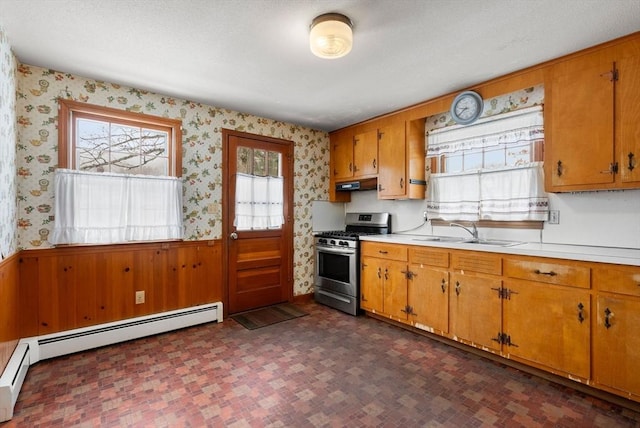 kitchen with wallpapered walls, wainscoting, and gas stove