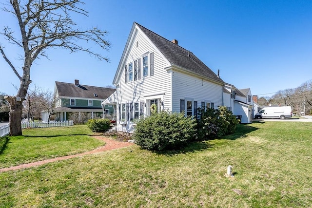 1243 Main St Unit 1243, Barnstable, MA 02635 - view of property exterior featuring a lawn, fence, a chimney, and roof with shingles