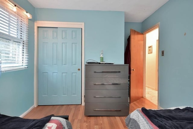 bedroom with wood finished floors, a closet, and baseboards
