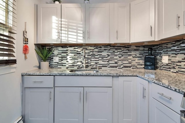 kitchen with a sink, decorative backsplash, and white cabinets