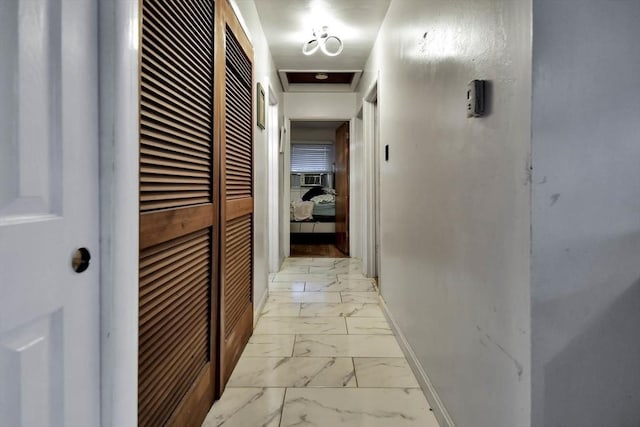 hallway with light marble finish floors, baseboards, and a heating unit