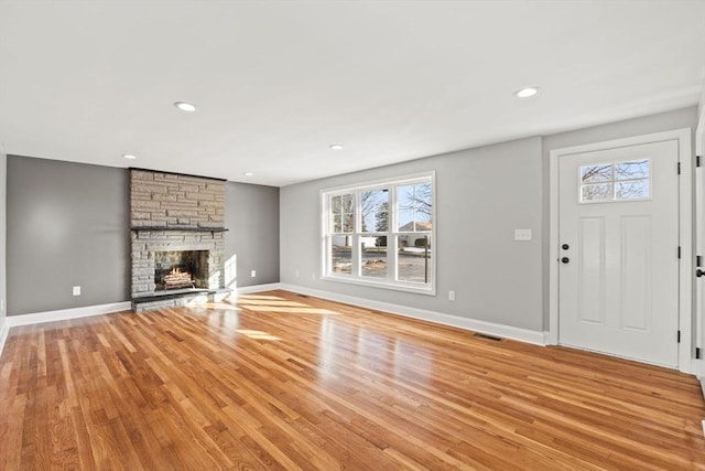 unfurnished living room with a stone fireplace and light hardwood / wood-style flooring