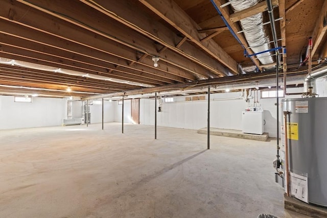 basement with a healthy amount of sunlight, washer / clothes dryer, and gas water heater