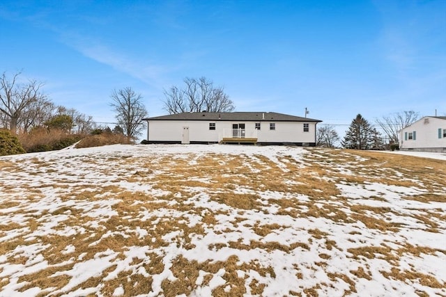 snow covered rear of property with a deck