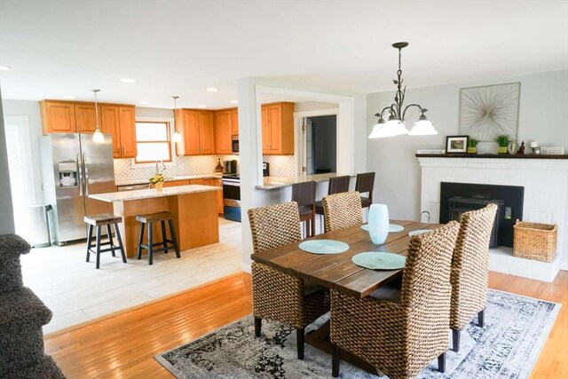 6 Sunrise, Auburn, MA 01501 - dining room featuring light wood finished floors, a brick fireplace, and a chandelier