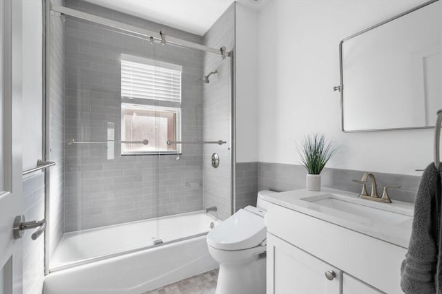 bathroom with toilet, bath / shower combo with glass door, and vanity