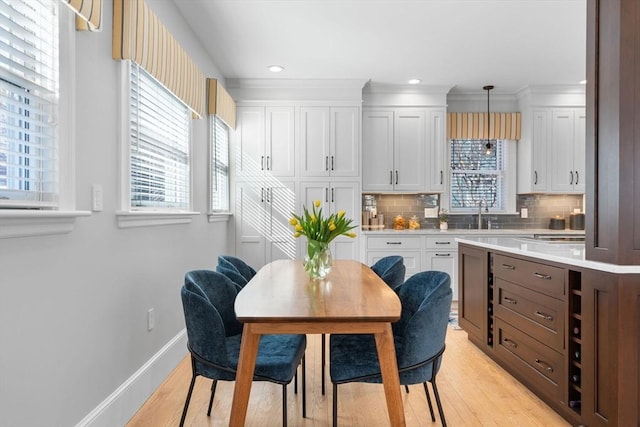 kitchen featuring baseboards, white cabinets, light countertops, hanging light fixtures, and tasteful backsplash