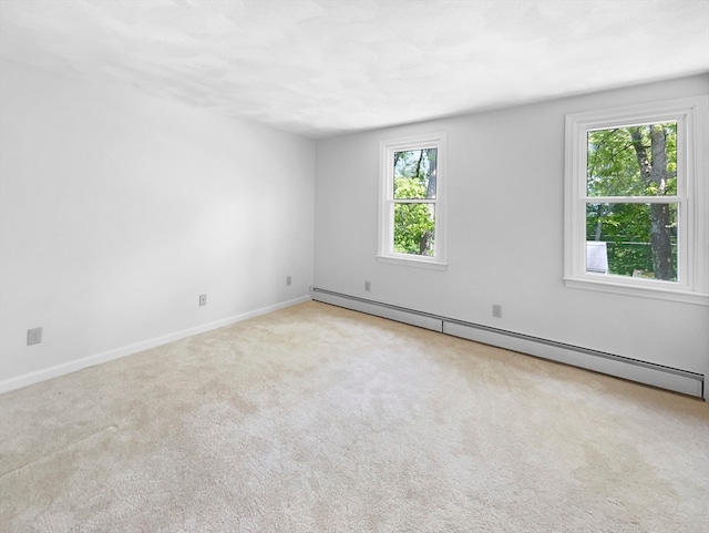 empty room with baseboard heating, light carpet, and a healthy amount of sunlight