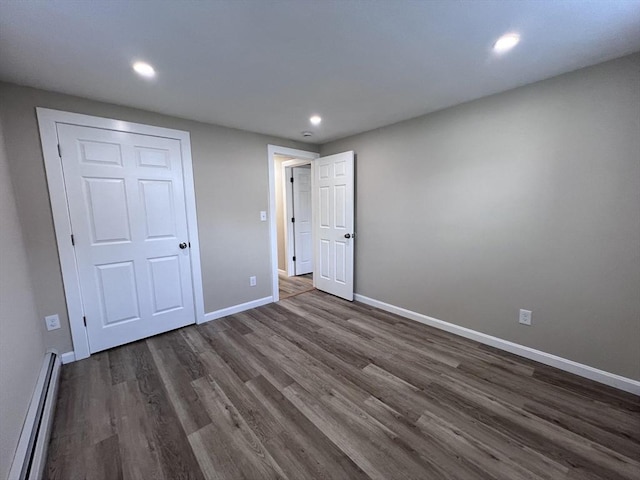 12 Woodland St Unit 12, Everett, MA 02149 - unfurnished bedroom featuring a baseboard radiator, dark wood-style floors, baseboards, and recessed lighting