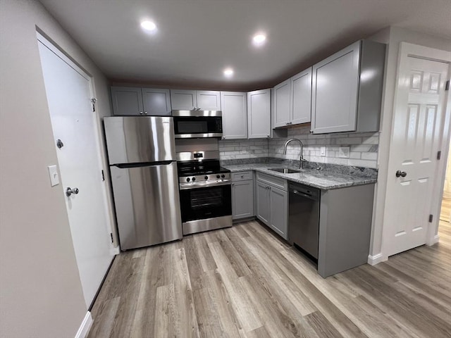 12 Woodland St Unit 12, Everett, MA 02149 - kitchen with appliances with stainless steel finishes, a sink, light wood-type flooring, gray cabinets, and light stone counters