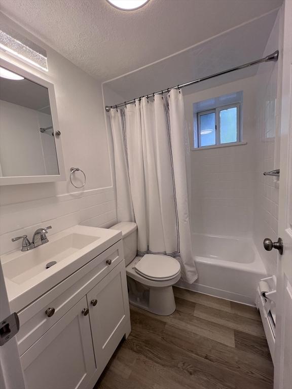 12 Woodland St Unit 12, Everett, MA 02149 - full bathroom with wood finished floors, toilet, a textured ceiling, vanity, and shower / bath combo