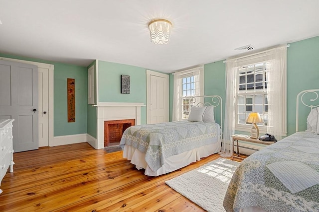228 Main St, Groton, MA 01450 - bedroom with a closet, a fireplace with flush hearth, hardwood / wood-style floors, visible vents, and baseboards