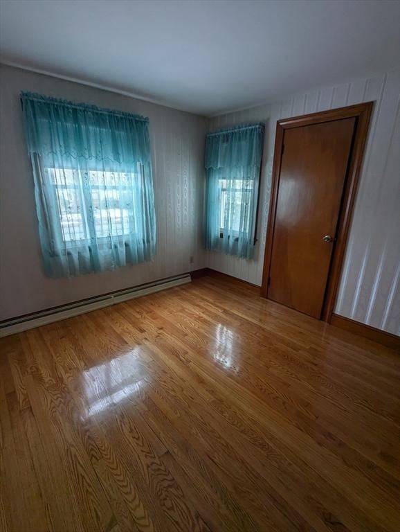 unfurnished room with a baseboard radiator and wood finished floors