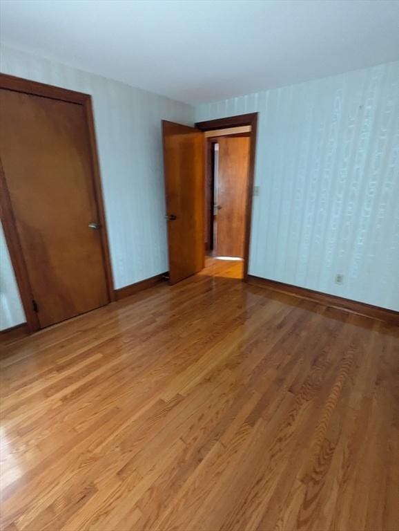 spare room with baseboards and light wood finished floors
