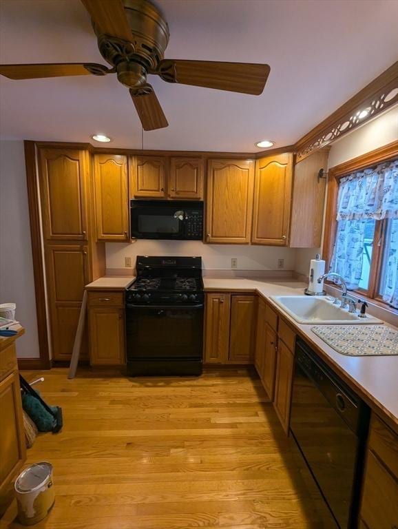 kitchen with a sink, black appliances, light wood-style flooring, and light countertops