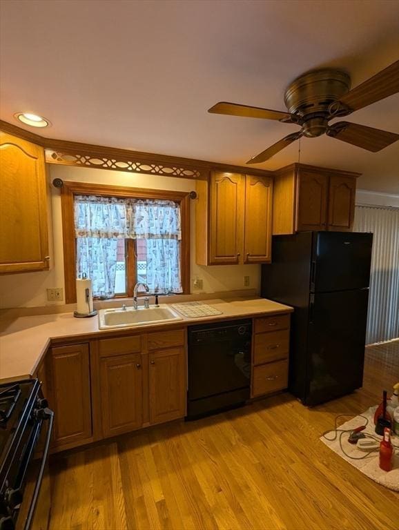 kitchen with ceiling fan, a sink, black appliances, light countertops, and light wood-style floors