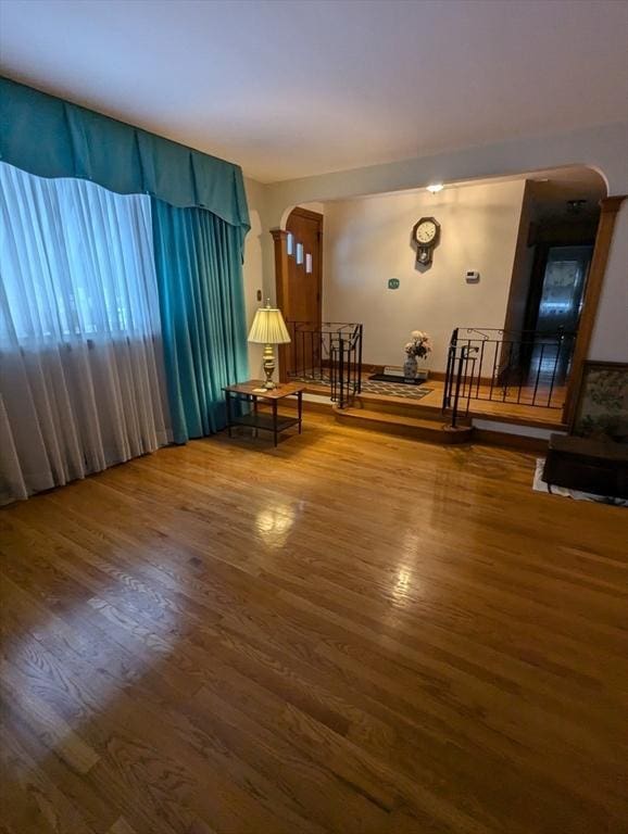 unfurnished room featuring arched walkways and wood finished floors
