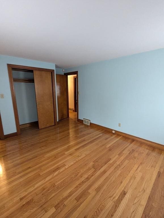 unfurnished bedroom featuring visible vents, light wood-style floors, a closet, and baseboards