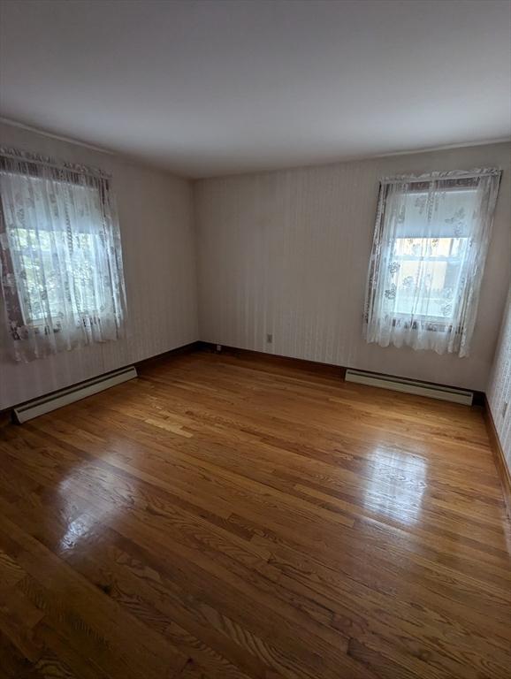 empty room featuring baseboard heating and wood finished floors