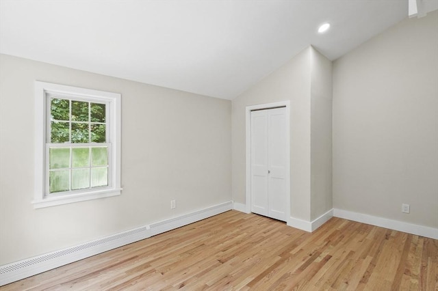 unfurnished bedroom featuring light wood-type flooring, baseboards, vaulted ceiling, and a closet