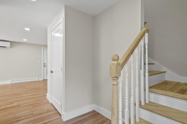 stairs with recessed lighting, a baseboard heating unit, wood finished floors, baseboards, and a wall mounted air conditioner