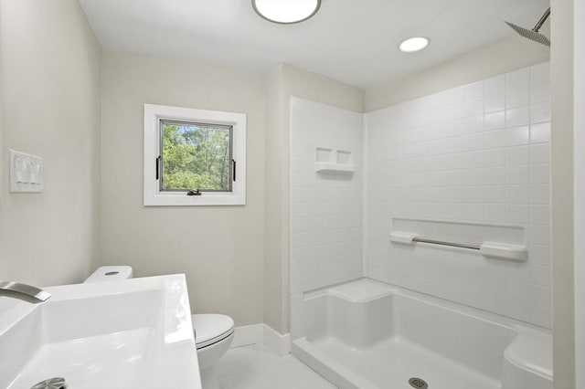 bathroom featuring a shower, baseboards, a sink, and toilet