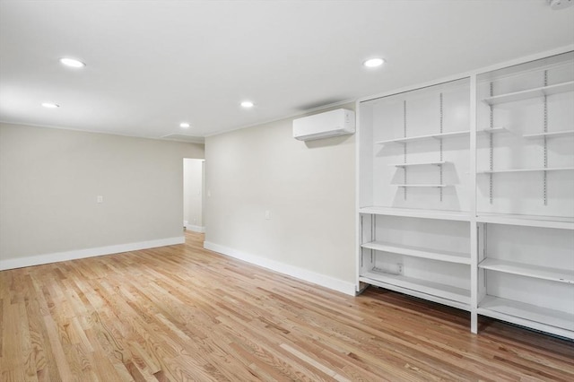 basement featuring light wood-type flooring, an AC wall unit, baseboards, and recessed lighting