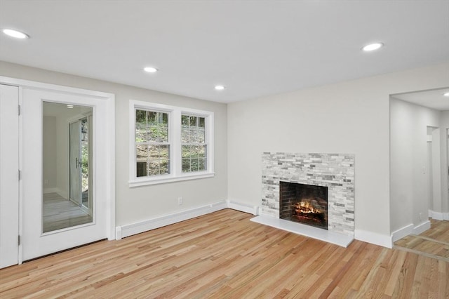 unfurnished living room featuring recessed lighting, baseboards, wood finished floors, and a stone fireplace