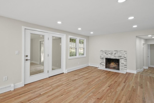 unfurnished living room with light wood-type flooring, a baseboard radiator, recessed lighting, and a stone fireplace