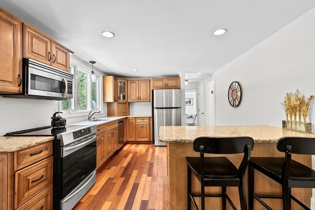 59 First Parish Rd, Norwell, MA 02061 - kitchen with appliances with stainless steel finishes, a breakfast bar area, brown cabinets, light wood-style floors, and recessed lighting