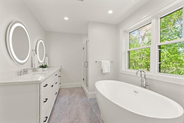 full bath featuring vanity, marble finish flooring, a shower stall, a freestanding bath, and recessed lighting