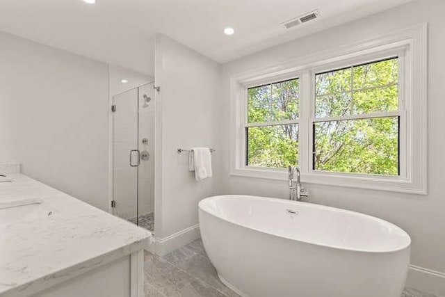 bathroom featuring baseboards, marble look tile flooring, a freestanding bath, a shower stall, and recessed lighting