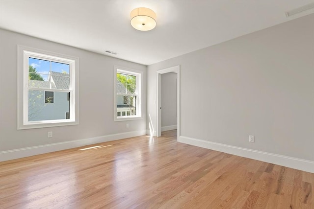 spare room featuring baseboards and light wood finished floors