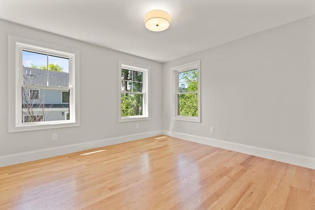 empty room featuring healthy amount of natural light, baseboards, and light wood-style flooring