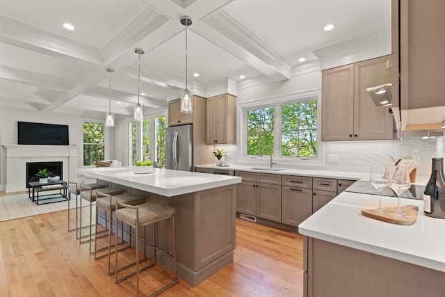 kitchen with stainless steel fridge, a sink, plenty of natural light, light wood-style flooring, and beam ceiling