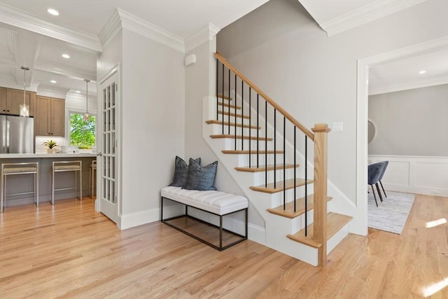 staircase with wood finished floors, crown molding, recessed lighting, and a decorative wall