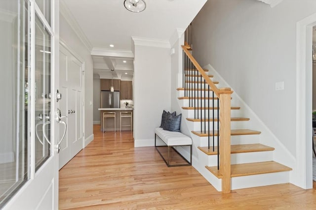 foyer featuring stairs, light wood-type flooring, recessed lighting, crown molding, and baseboards