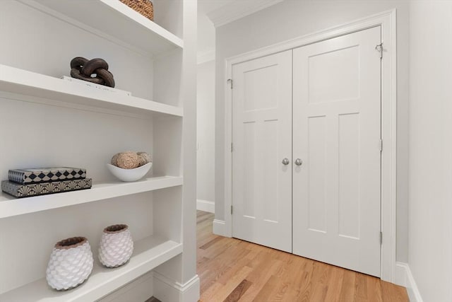 mudroom featuring light wood-style flooring, crown molding, and baseboards