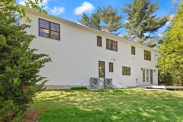 rear view of property featuring ac unit and a lawn