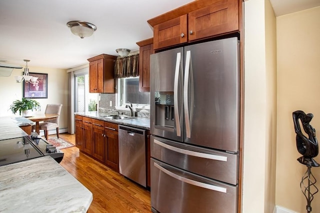 136 Maryland Ave, Somerset, MA 02726 - kitchen featuring stainless steel appliances, a sink, light wood finished floors, backsplash, and hanging light fixtures