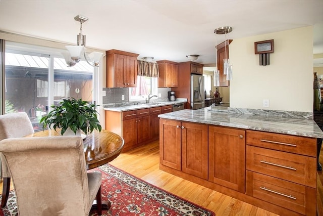 136 Maryland Ave, Somerset, MA 02726 - kitchen featuring stainless steel appliances, light wood finished floors, a sink, brown cabinets, and hanging light fixtures