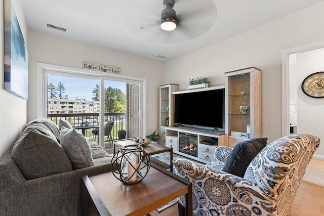 living room with ceiling fan, wood finished floors, and visible vents
